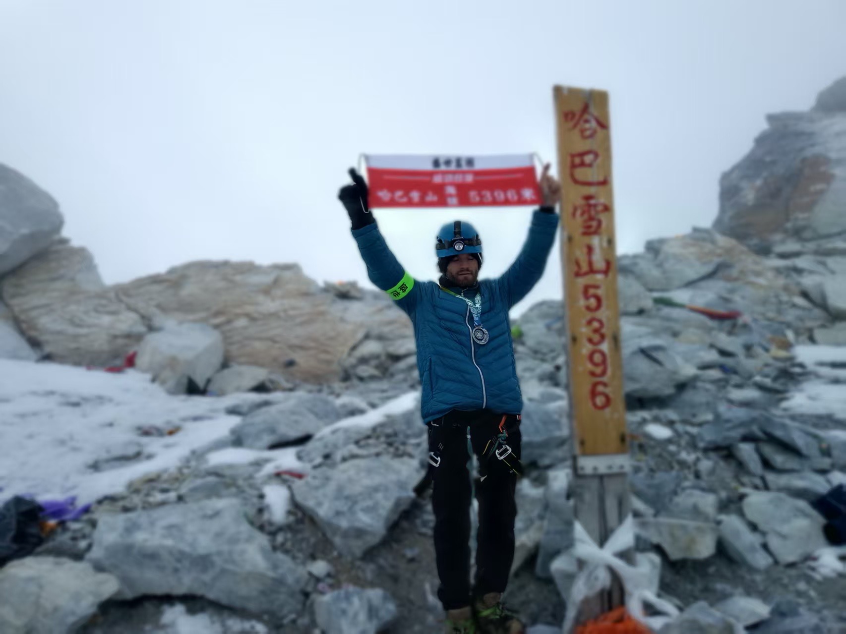 A guest celebrating at the Haba Snow Mountain summit marker