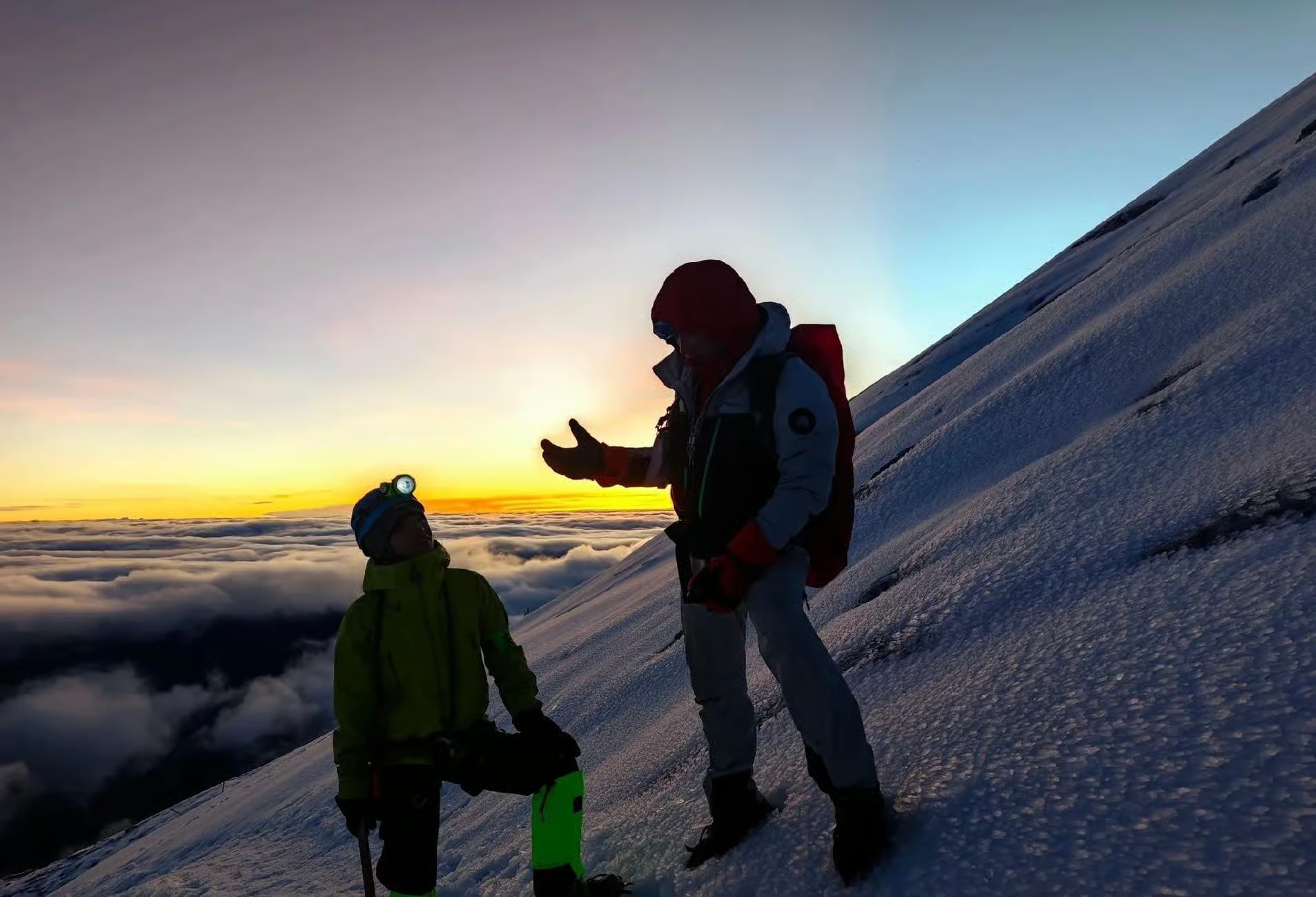 Two climbers ascending a snowy slope on Haba Snow Mountain before sunrise