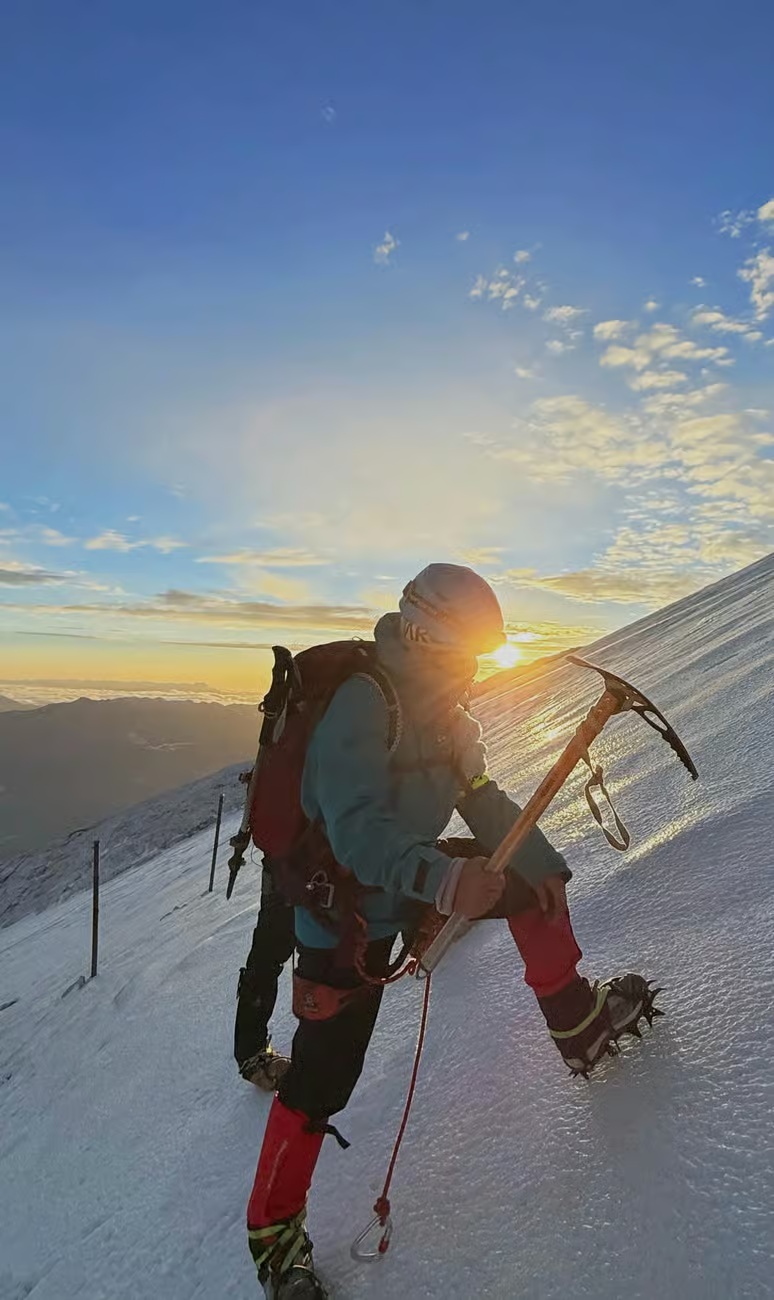 A climber wearing crampons and using an ice axe on Haba Snow Mountain