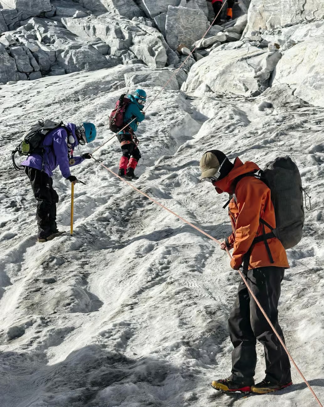 Climbers moving as a rope team across an icy section on Haba Snow Mountain